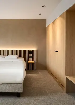 a bedroom with a bed and wooden cabinets at Hotel Chamade in Ghent