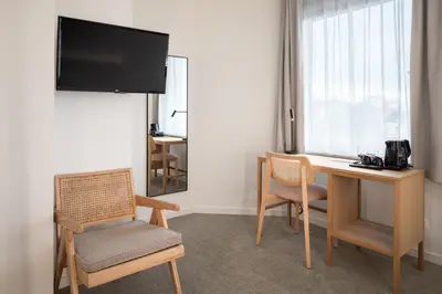 a room with a desk and chairs and a television at Hotel Chamade in Ghent