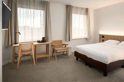 a hotel room with a bed and a desk and a bed and a desk at Hotel Chamade in Ghent