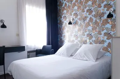 a bedroom with a white bed with a floral wall at Hotel Queen Anne in Brussels