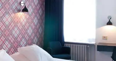 a bedroom with a bed and a chair and a window at Hotel Queen Anne in Brussels