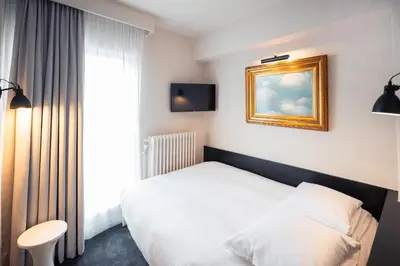 a hotel room with a white bed and a window at Hotel Queen Anne in Brussels