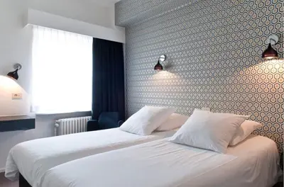 a bedroom with a white bed with two pillows at Hotel Queen Anne in Brussels