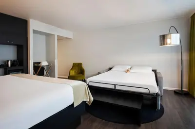 a hotel room with two beds and a lamp at Thon Hotel Bristol Stephanie in Brussels