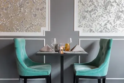 a table with two green chairs in a dining room at Thon Hotel Bristol Stephanie in Brussels