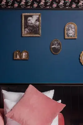 a blue wall with framed pictures and a pink pillow at Craves in Brussels