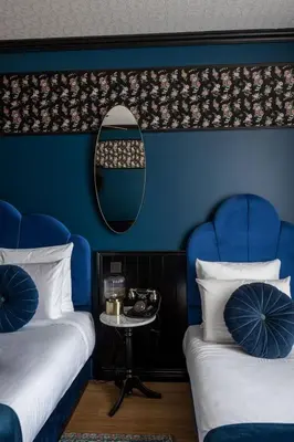 two beds in a room with blue walls and a mirror at Craves in Brussels
