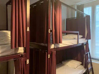 two bunk beds in a room with red curtains at Safestay Brussels Grand Place in Brussels