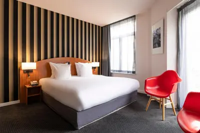 a hotel room with a bed and a red chair at Aris Grand Place Hotel in Brussels