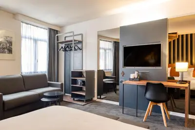 a living room with a couch and a desk with a tv at Aris Grand Place Hotel in Brussels