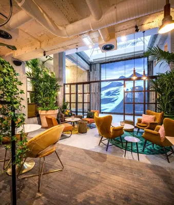 a lobby with chairs and tables and plants at Hotel Indigo Brussels - City by IHG in Brussels