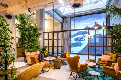 a lobby with chairs and tables and a large window at Hotel Indigo Brussels - City by IHG in Brussels