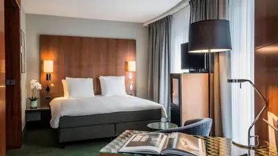 a hotel room with a bed and a table with a book at NH Brussels EU Berlaymont in Brussels