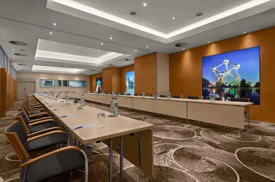 a conference room with tables and chairs and a large screen at NH Brussels EU Berlaymont in Brussels