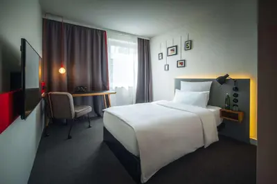 a hotel room with a white bed and a desk at pentahotel Brussels City Centre in Brussels