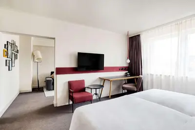 a hotel room with a bed and a desk and a tv at pentahotel Brussels City Centre in Brussels