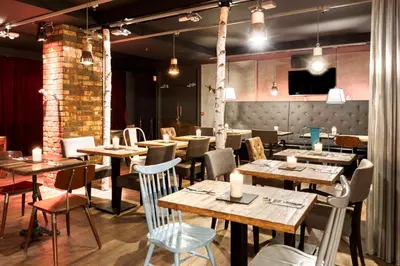 a restaurant with wooden tables and chairs and lights at pentahotel Brussels City Centre in Brussels