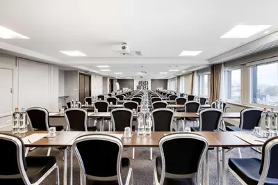 an empty room with tables and chairs and windows at pentahotel Brussels City Centre in Brussels