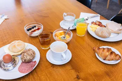 a wooden table with plates of breakfast foods and drinks at Hotel Corsendonk Viane in Turnhout