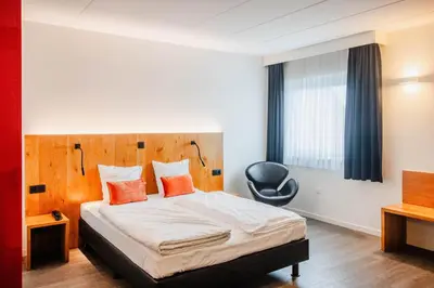a hotel room with a bed and a chair at Hotel Corsendonk Viane in Turnhout