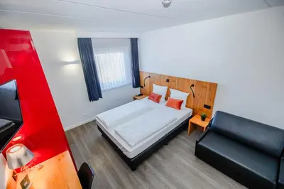 a small bedroom with a bed and a couch at Hotel Corsendonk Viane in Turnhout