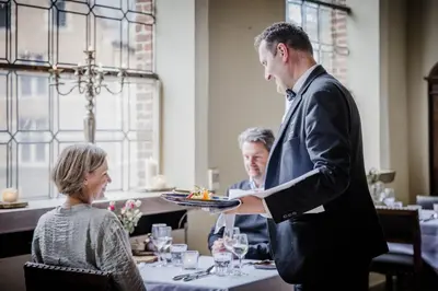 a man holding a plate of food in a restaurant at Priorij Corsendonk in Oud-Turnhout