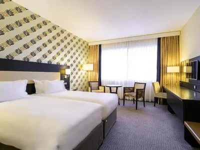 a hotel room with two beds and a desk at Mercure Antwerp City South in Antwerp