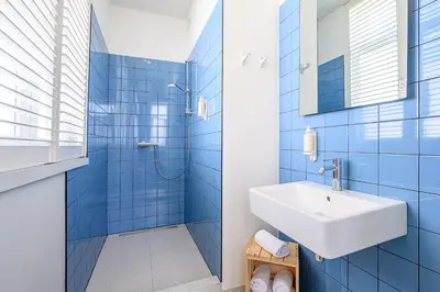a blue tiled bathroom with a sink and a shower at Hotel La Grande Cloche in Brussels