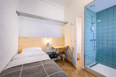 a small bedroom with a bed and a shower at Hotel La Grande Cloche in Brussels