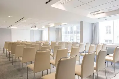an empty room with rows of chairs and windows at NH Collection Brussels Centre in Brussels