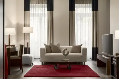 a living room with a white couch and a tv at NH Collection Brussels Centre in Brussels