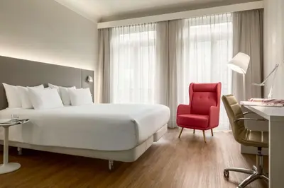 a hotel room with a bed and a red chair at NH Collection Brussels Centre in Brussels
