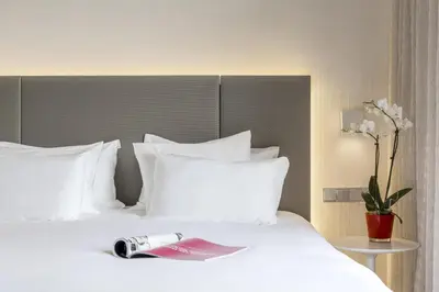 a book laying on a bed with white pillows at NH Collection Brussels Centre in Brussels