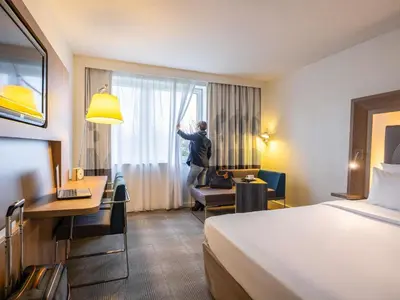 a man is looking out of a window in a hotel room at Novotel Brussels Airport in Diegem