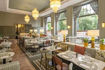 a restaurant with tables and chairs and large windows at DoubleTree By Hilton Brussels City in Brussels