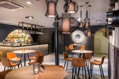 a restaurant with tables and chairs and pendant lights at Martin's Château Du Lac in Genval