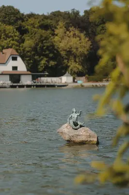 a statue of a man sitting on a rock in the water at Martin's Château Du Lac in Genval