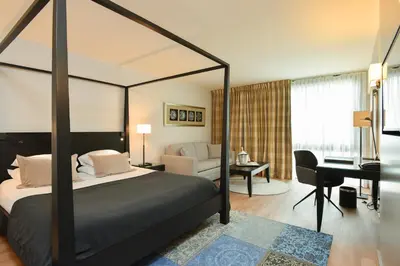 a bedroom with a canopy bed with a desk and a piano at Martin's Château Du Lac in Genval