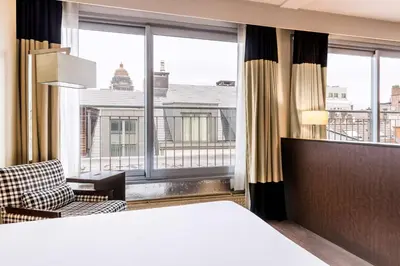 a hotel room with a bed and a large window at NH Brussels Stéphanie in Brussels