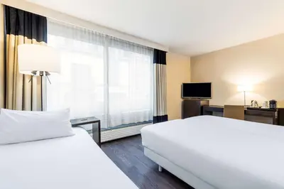 a hotel room with a bed and a large window at NH Brussels Stéphanie in Brussels