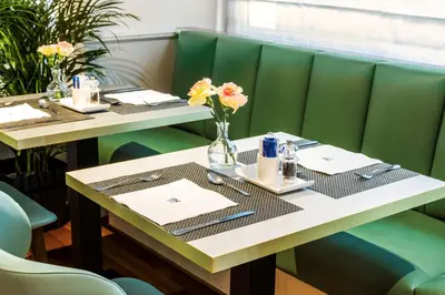 two tables in a restaurant with flowers on them at NH Brussels Stéphanie in Brussels