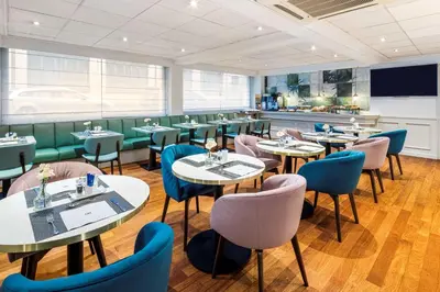 a restaurant with tables and chairs and a bar at NH Brussels Stéphanie in Brussels