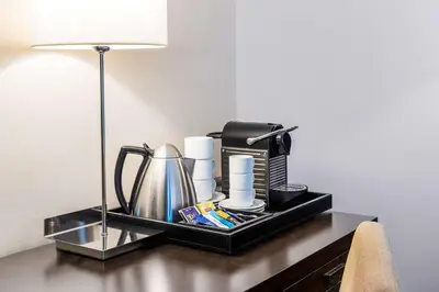 a tray with a coffee maker and a lamp on a table at NH Brussels Stéphanie in Brussels