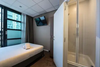 a bathroom with a bed and a shower and a television at Hotel Docklands Antwerpen in Antwerp