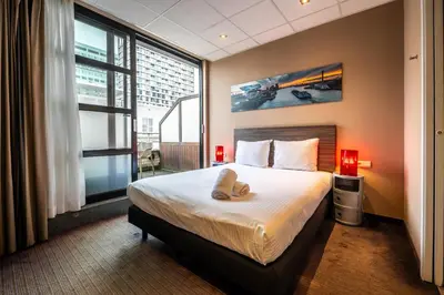 a bedroom with a bed and a large window at Hotel Docklands Antwerpen in Antwerp