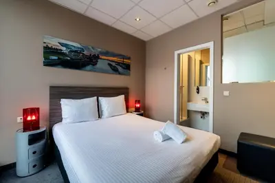 a bedroom with a large white bed with two red lamps at Hotel Docklands Antwerpen in Antwerp