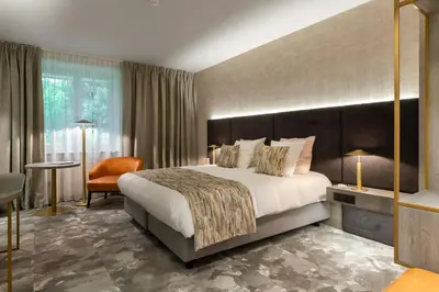 a hotel room with a large bed and a chair at Van der Valk Waterloo in Waterloo