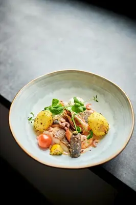 a bowl of food with meat and potatoes on a table at Van der Valk Waterloo in Waterloo