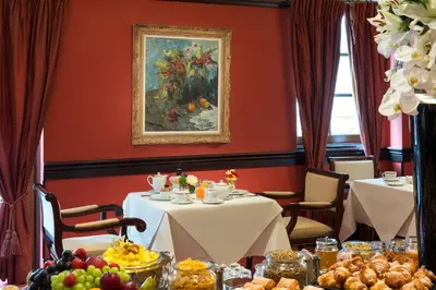 a dining room with two tables and a painting at Warwick Grand-Place Brussels in Brussels