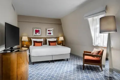 a bedroom with a bed and a flat screen tv at Warwick Grand-Place Brussels in Brussels